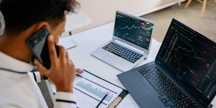 South Korean investors analyzing cryptocurrency charts on digital devices in a modern office.