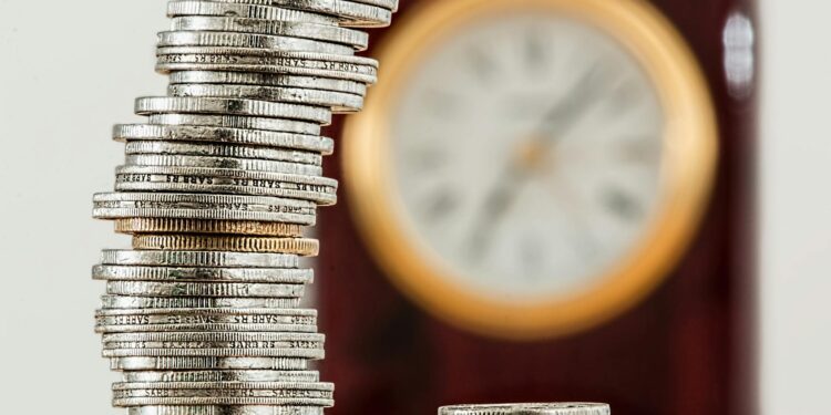 Cryptocurrency coins stacked on financial documents with a clock indicating delays.