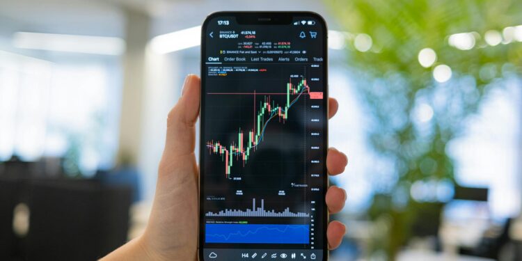 Hand holding a smartphone displaying a digital wallet app with cryptocurrency icons on screen.