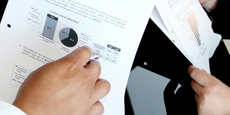 A financial analyst reviews charts and documents related to OCC trust bank regulations.