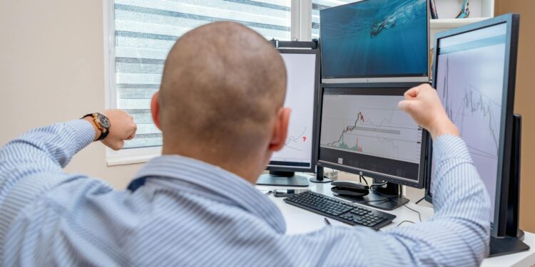 Traders at computer screens display the NYSE logo and charts of tokenized stock transactions.