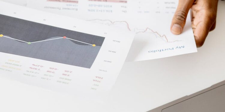 Person reviewing cryptocurrency options on a laptop with financial documents and charts nearby.
