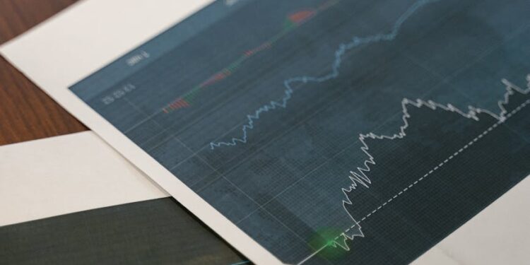 Bitcoin coins stacked with financial charts and graphs in the background.