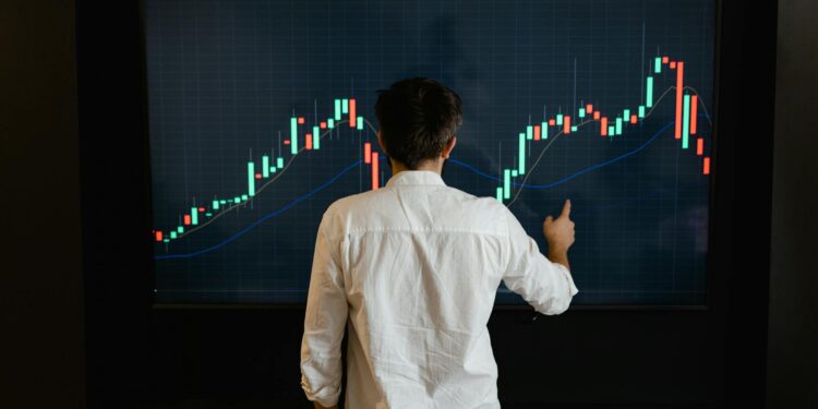 A person analyzes cryptocurrency charts with Bitcoin icons and financial graphs on a screen.