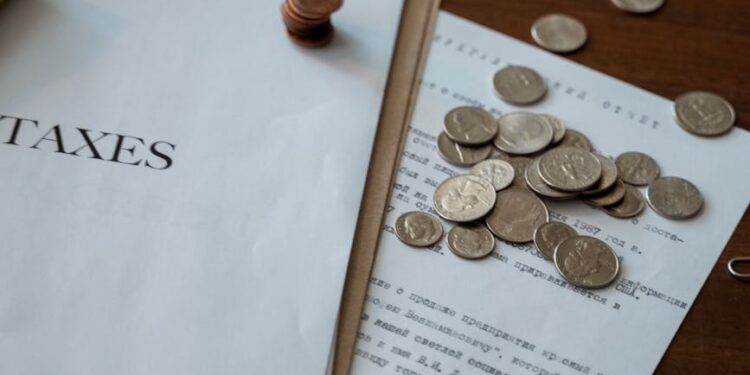 A close-up of cryptocurrency coins with tax documents and a calculator, symbolizing regulatory challenges.