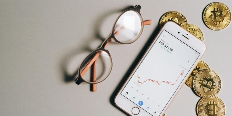 Smartphone displaying cryptocurrency apps with financial graphs in the background.