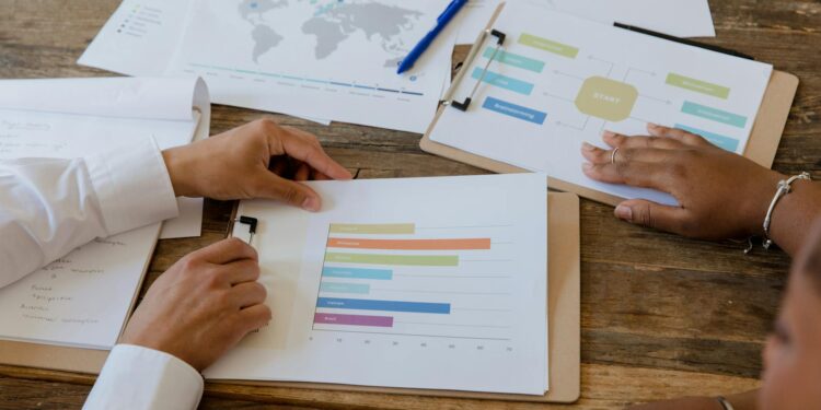 Two officials discussing regulatory plans over a table with cryptocurrency charts and documents.