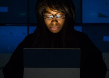 Engineer working on XRPL code with crypto graphics on screens nearby.