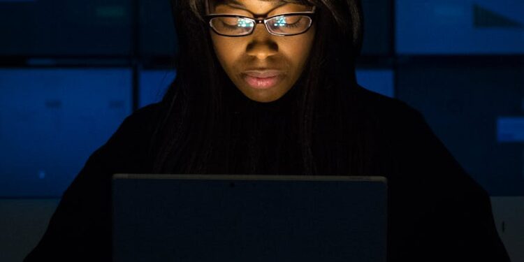 Engineer working on XRPL code with crypto graphics on screens nearby.