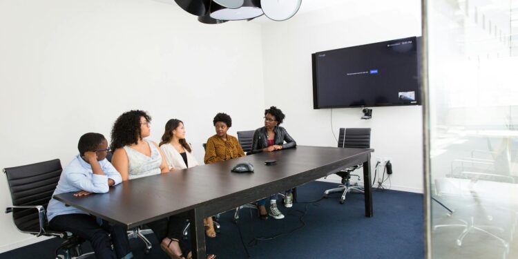 A group of business professionals discuss blockchain technology at a conference table.