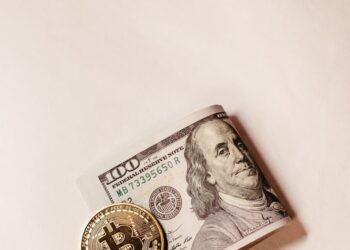 A Bitcoin coin with a dollar sign overlay and financial graphs in the background.