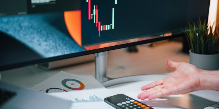 A person analyzing cryptocurrency charts on a computer with a legal document in focus.