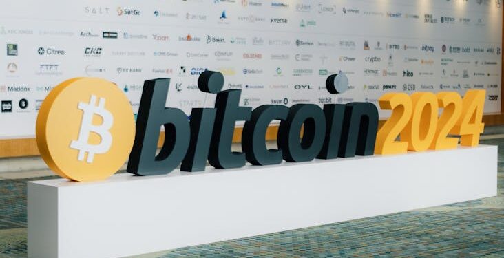 David Solomon speaking at a financial conference with Bitcoin symbols in the background.