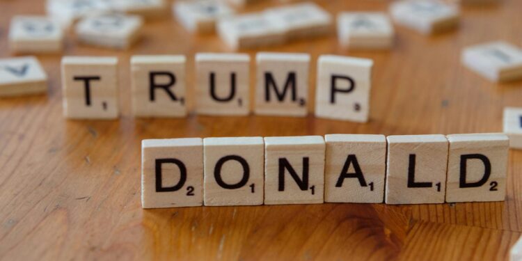 Former President Trump speaking at a podium with cryptocurrency graphics in the background.