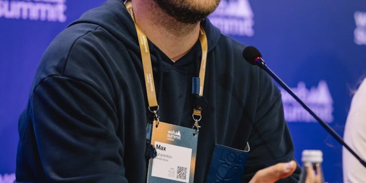 Peter Thiel speaking at a tech conference with crypto graphics in the background.