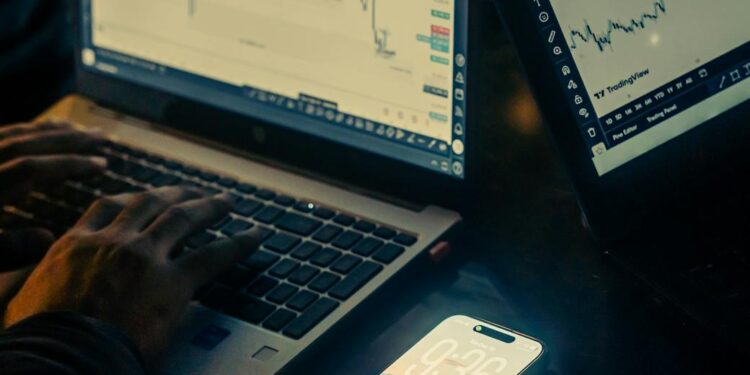Two people being escorted by police, with digital currency graphs displayed behind them.