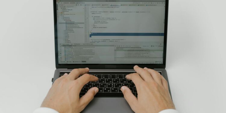 A hacker manipulating code on a computer, with cryptocurrency graphics in the background.