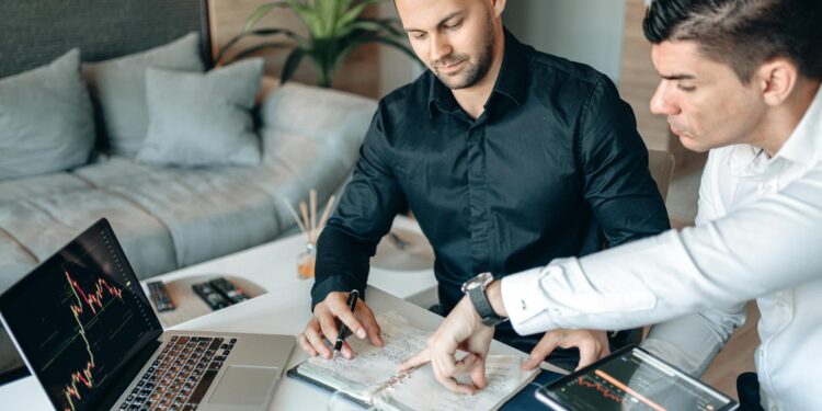 Business professionals discussing cryptocurrency strategies with financial charts in the background.