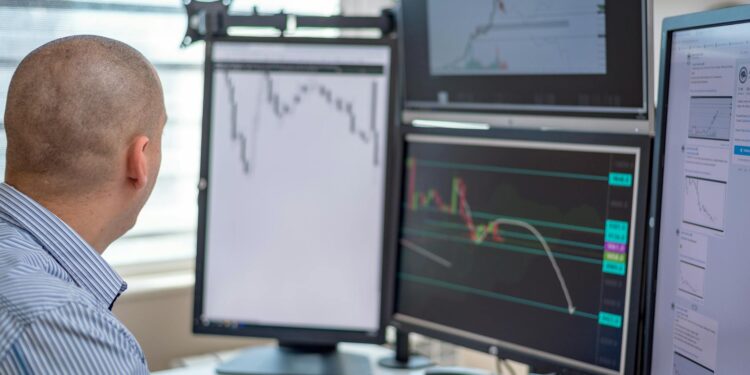 A trader examines Bitcoin charts on multiple screens with financial data displayed.