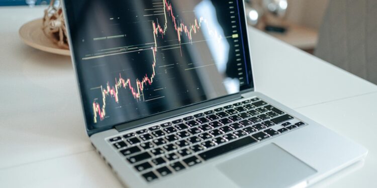 Two financial analysts discussing stock charts with a digital display of cryptocurrency values.