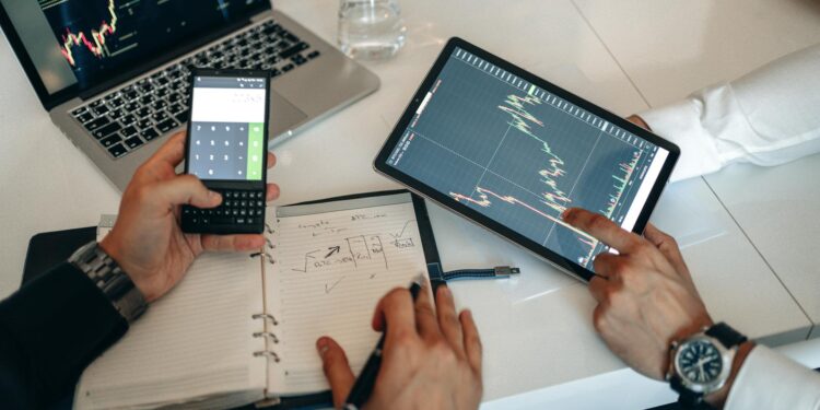 A trader analyzes market data on a laptop with cryptocurrency charts and graphs displayed.