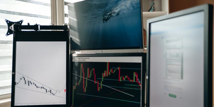 Charles Hoskinson sits at a desk, looking concerned with financial charts displaying losses.