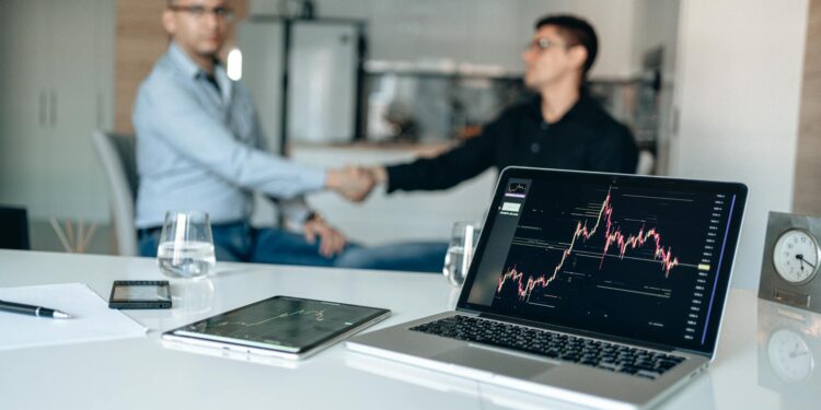 Business executives shaking hands with financial graphs and logos of Amazon and Nvidia in the background.