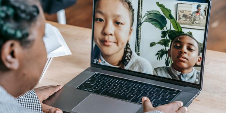 Students in a classroom learning about cryptocurrency with laptops and Bitcoin graphics on screen.