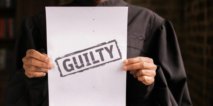 Sam Bankman-Fried speaking at a legal proceeding, gesturing with papers in hand.