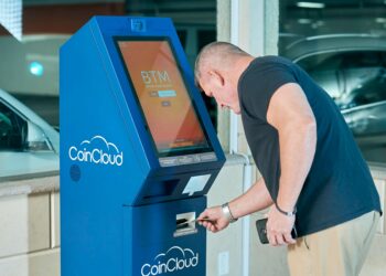 Bitcoin ATM screen displaying ID verification prompt amidst currency exchange graphics.