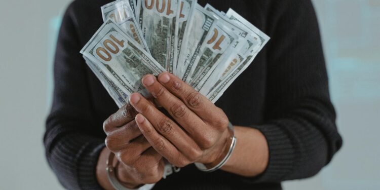 A man in handcuffs exits a courthouse amid reporters after a crypto fraud case.
