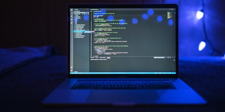 Teams of developers collaborate at a hackathon, laptops open and code on screens, focusing on AI.