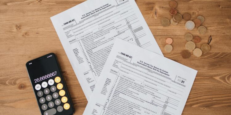 A calculator and cryptocurrency coins on a desk, symbolizing tax calculations on crypto gains.