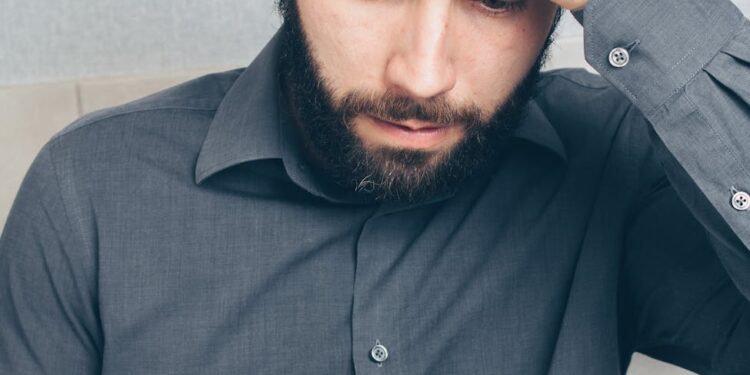 A man looking shocked at his phone, symbolizing financial loss from a crypto scam.