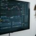 A trader analyzing Bitcoin price charts on multiple screens amidst digital currency graphics.