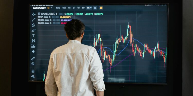 Financial analyst reviewing stock charts with cryptocurrency symbols overlayed.