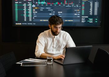 Financial analyst analyzing stock trends with cryptocurrency symbols in the background.