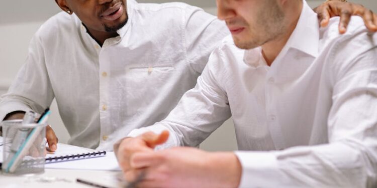 Employees working in a modern office, with some looking concerned and discussing changes.