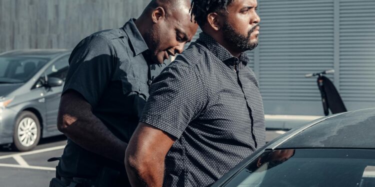 Police officers arrest individuals outside a financial office related to crypto trading.