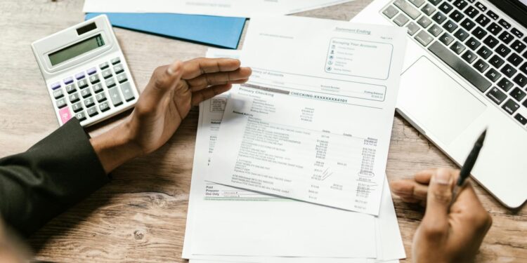 MrBeast reviewing the Teen Banking App Step on a laptop surrounded by financial documents.