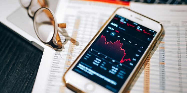 Close-up of a hand holding a smartphone displaying cryptocurrency market trends and news.