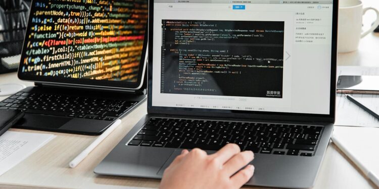 A developer coding on a laptop with Bitcoin and USDT logos displayed on the screen.