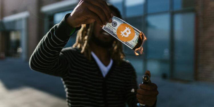 A person holding a cryptocurrency card with financial symbols in the background.