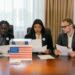 A group of diverse officials discussing cryptocurrency regulations at a conference table.