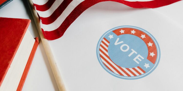 A representative holds a cryptocurrency symbol next to a financial chart and political campaign materials.