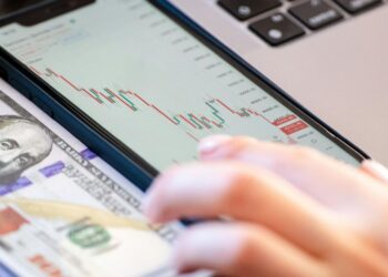Stock market graph with upward trend, symbols of finance, and dollar signs in the background.