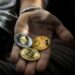 Two hands exchanging digital coins with a backdrop of blockchain graphics and financial symbols.