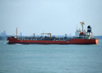A U.S. military vessel navigating through the Strait of Hormuz, with oil tankers in view.
