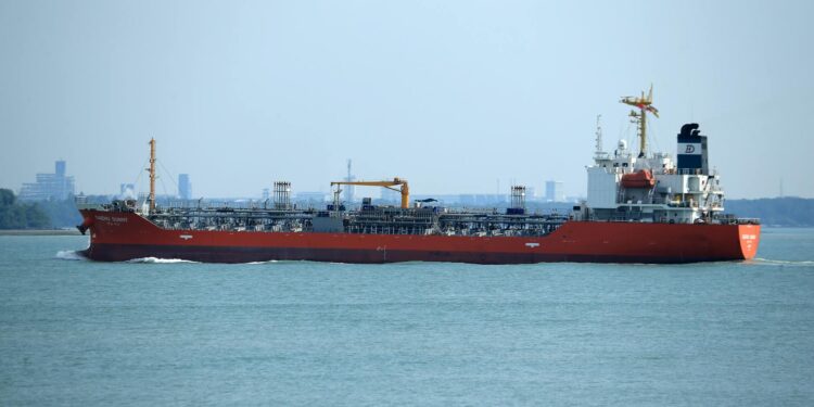 A U.S. military vessel navigating through the Strait of Hormuz, with oil tankers in view.