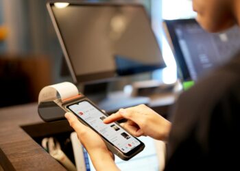 A smartphone displays a Bitcoin payment app with a merchant's payment terminal.